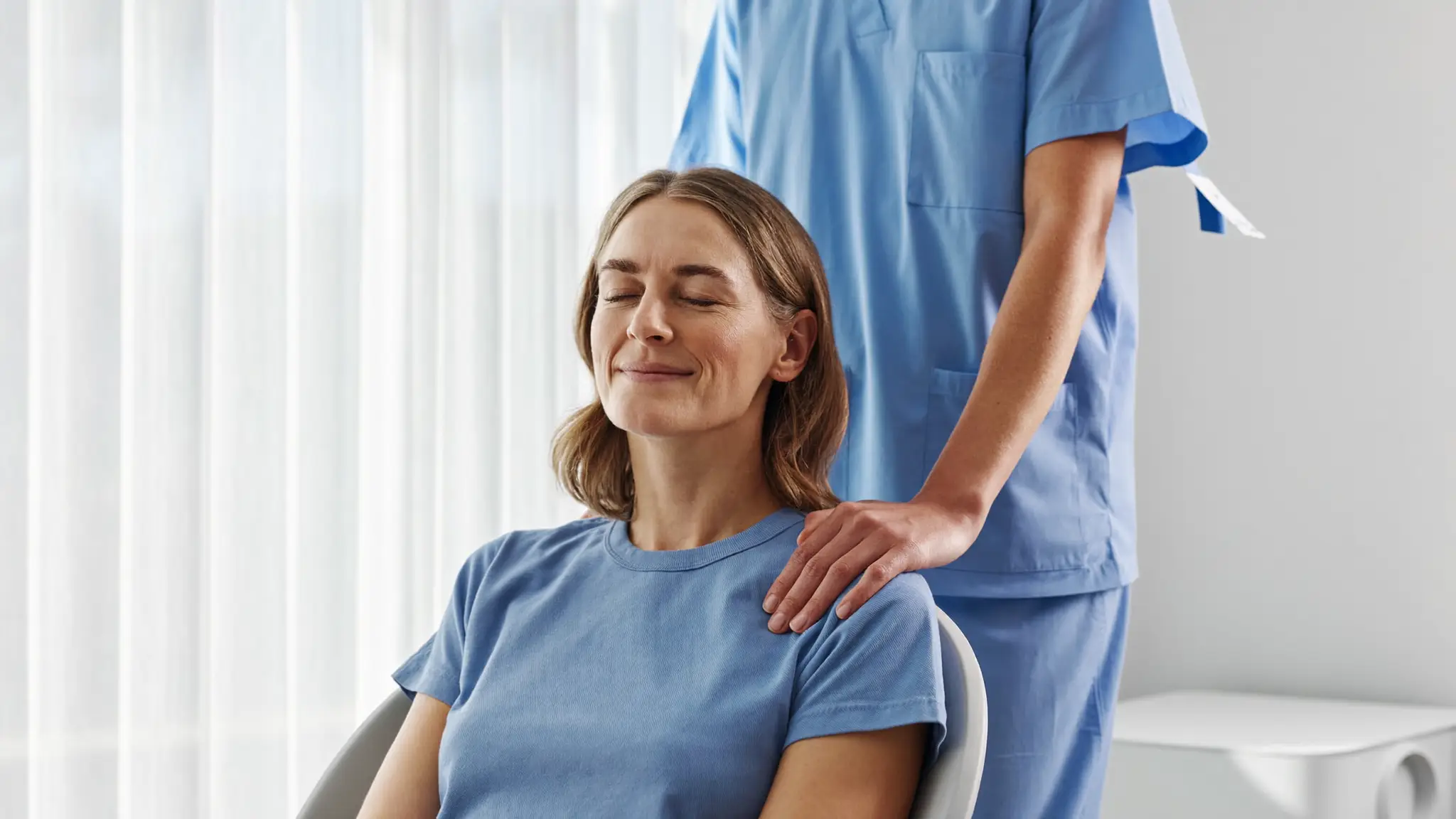 A patient at ease with her eyes closed, a caring hand resting on her shoulder
