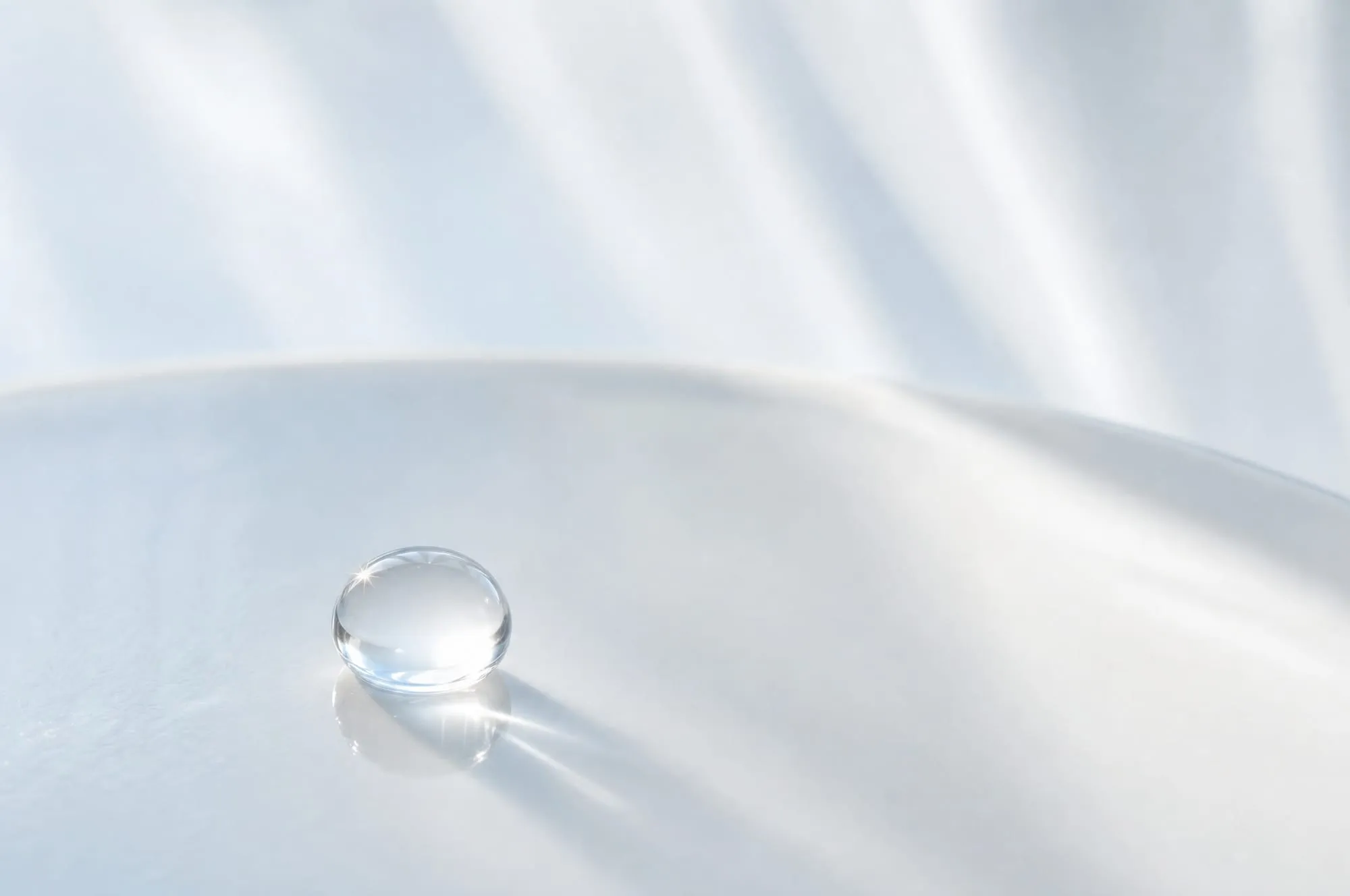 A droplet of clear resin catching light on a porcelain surface