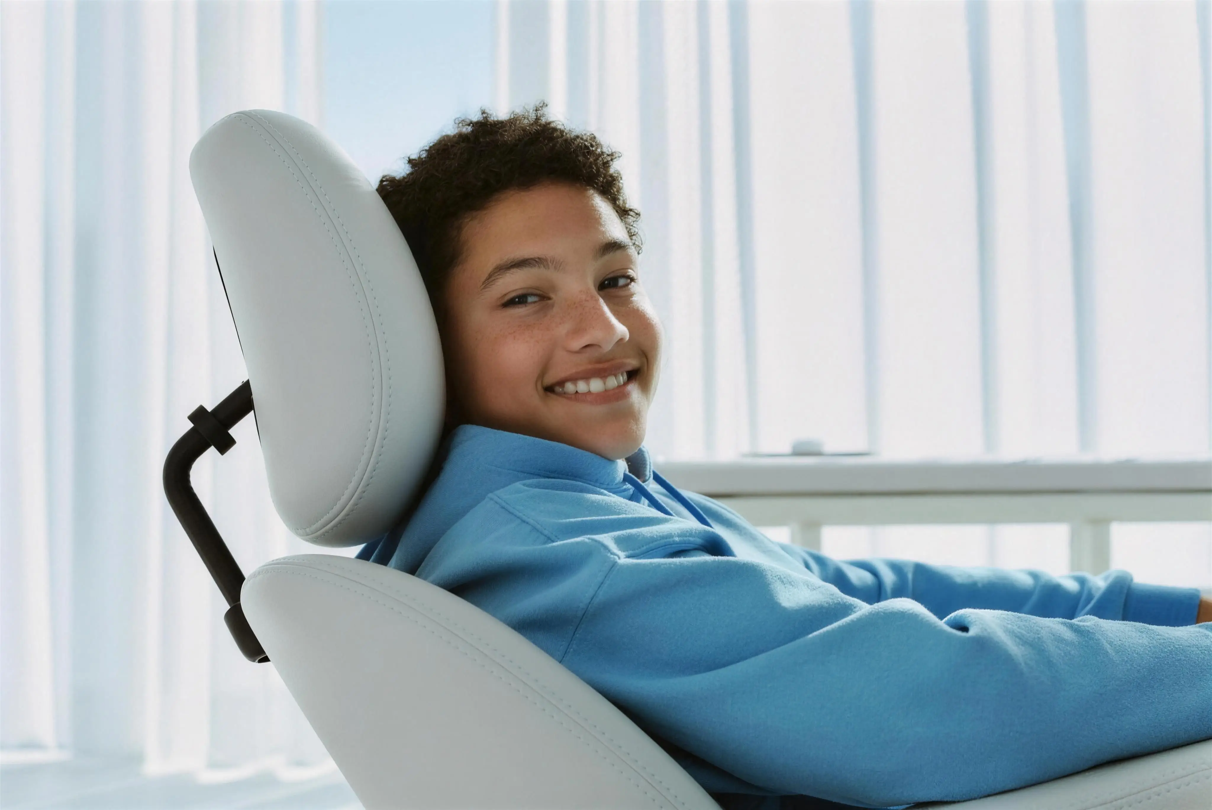 A young patient reclining in the dental chair, relaxed and smiling