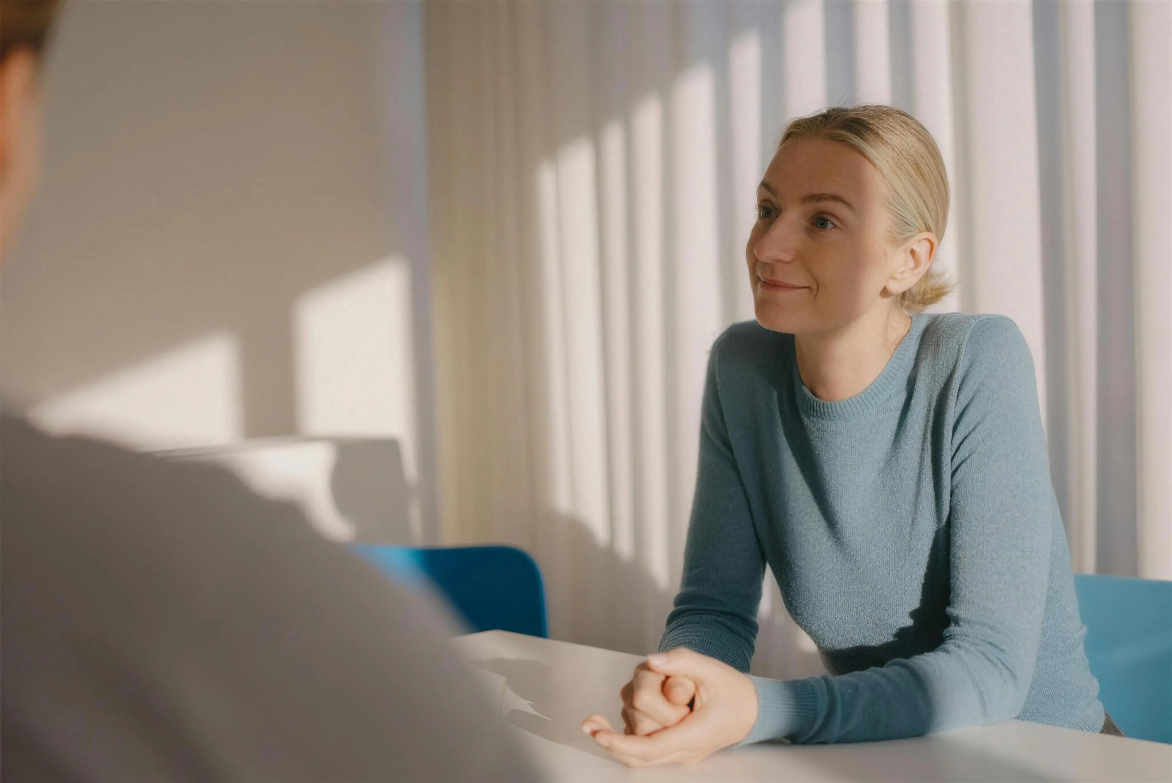 A patient at a consultation, listening with her hands folded